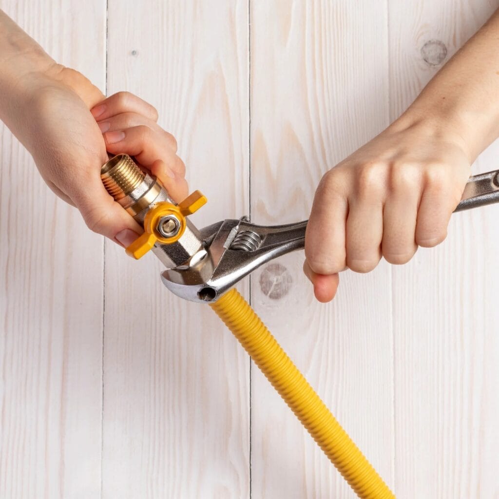 Gazownik Tychy, zdjęcie przedstawiające dokręcanie zaworu na żółtej rurze przez doświadczonego fachowca firmy Usługi gazownicze Instalacja3w1.